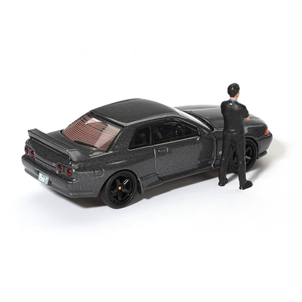 Mini GT 1:64 Nissan Skyline GT-R (R32) Nismo Gunmetal con figura de Matsuda – Colección Tsugio Matsuda PRESENTACIÓN EN CAJA